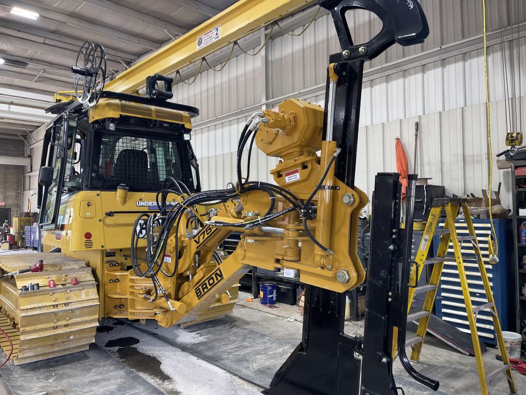 Close-up of heavy tracked utility equipment and hydraulic components inside a service facility