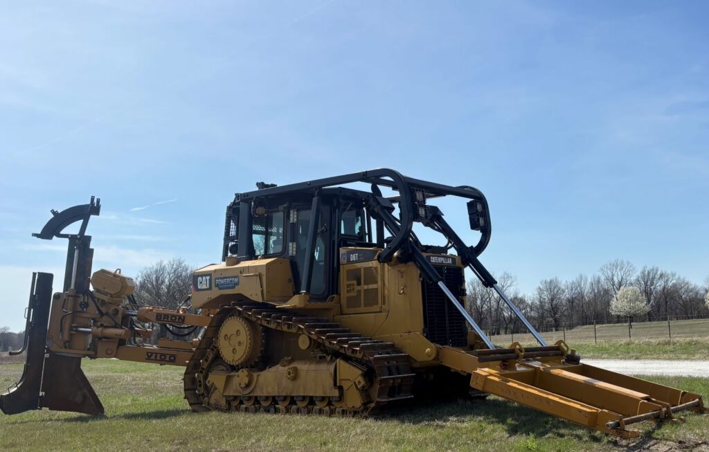 Caterpillar tracked dozer shown outdoors with heavy-duty blade and utility equipment