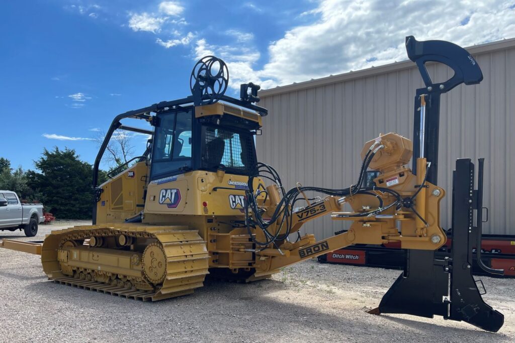 Yellow Caterpillar dozer with utility plow attachment parked outdoors for heavy construction work